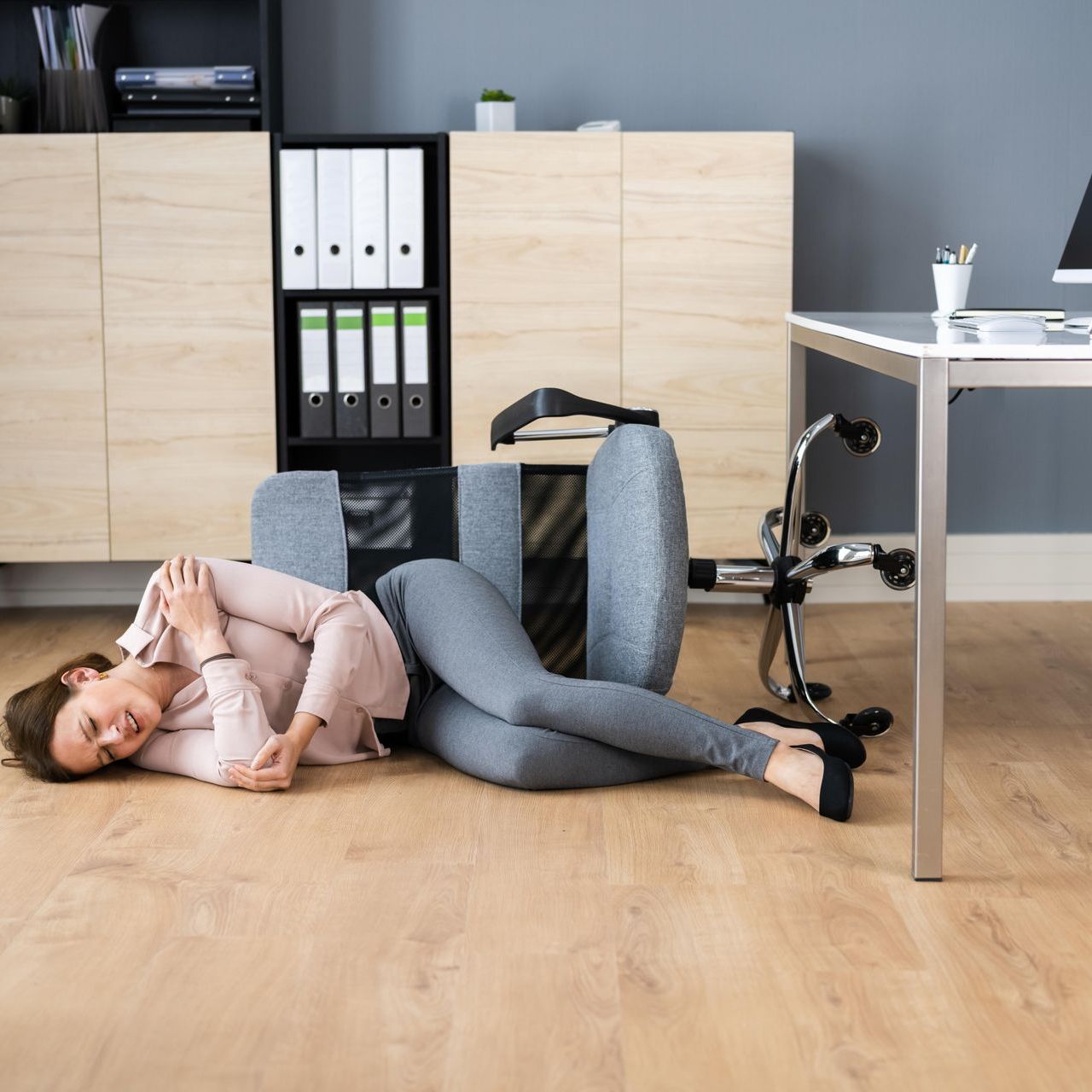 A woman is laying on the floor next to a chair