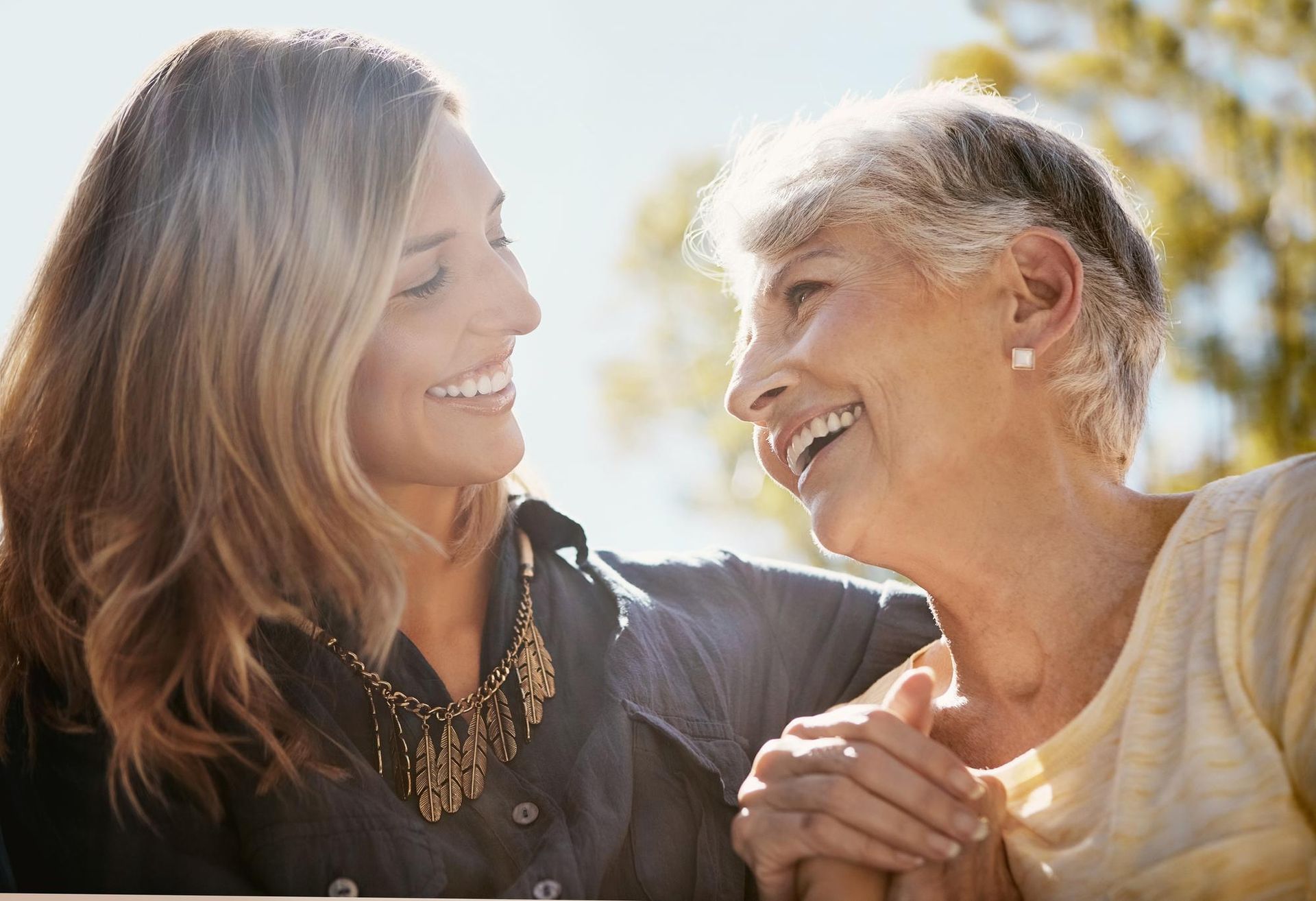 Two women are holding hands and smiling at each other.