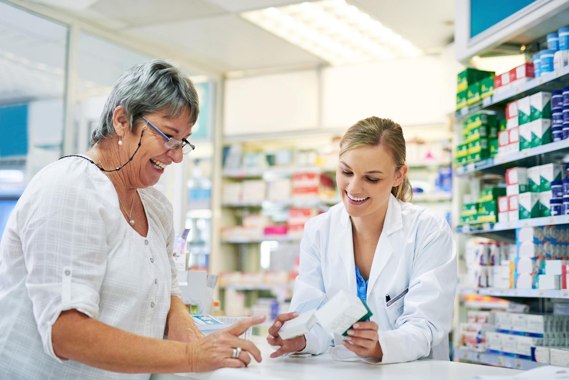 A female pharmacist is talking to an older woman in a pharmacy.