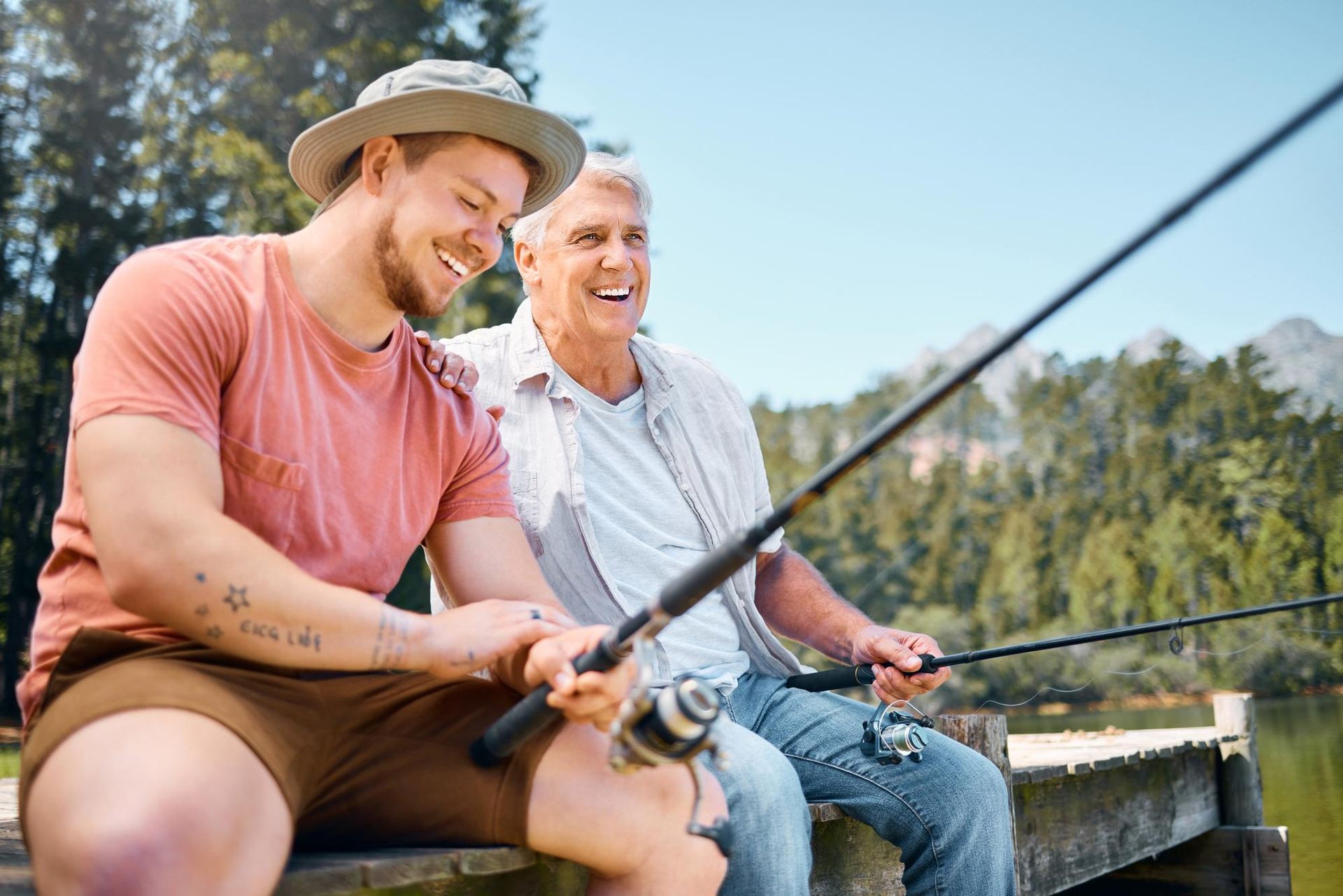 A man and a young man are sitting on a dock fishing.