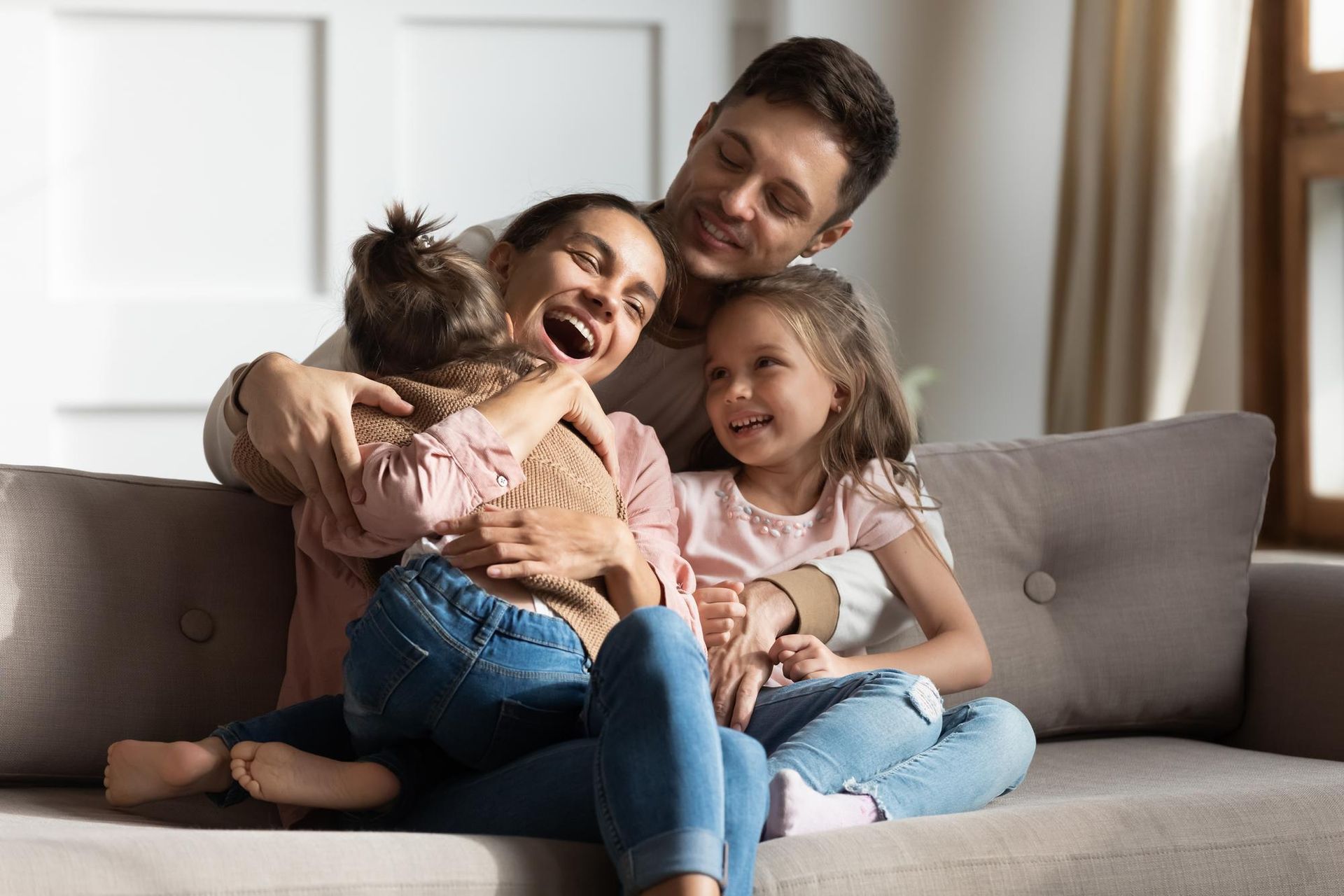 A family is sitting on a couch hugging each other.