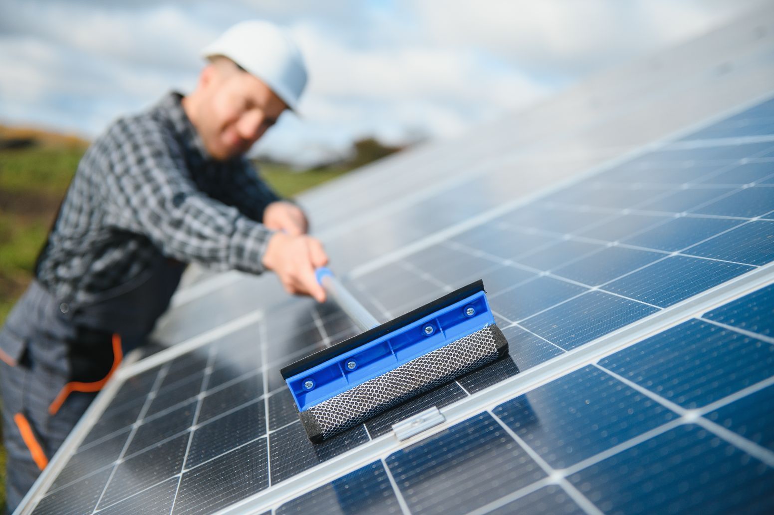 A Man Is Cleaning Solar Panels With A Brush — Hunter Smart Solar Cleaning In Nelson Bay, NSW