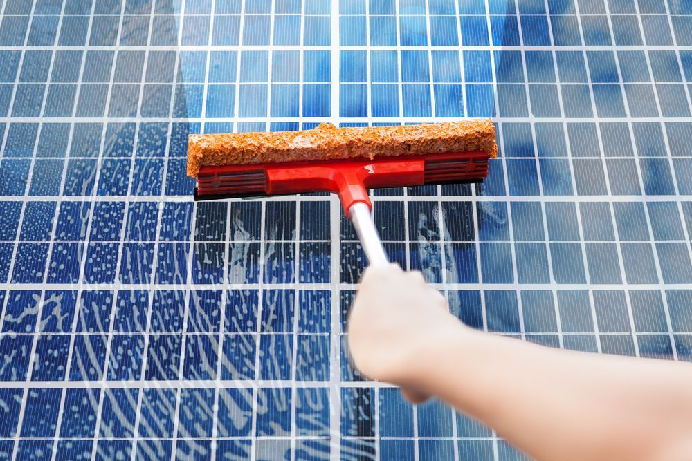 A Person Is Cleaning A Tiled Floor With A Squeegee — Hunter Smart Solar Cleaning In Corlette, NSW