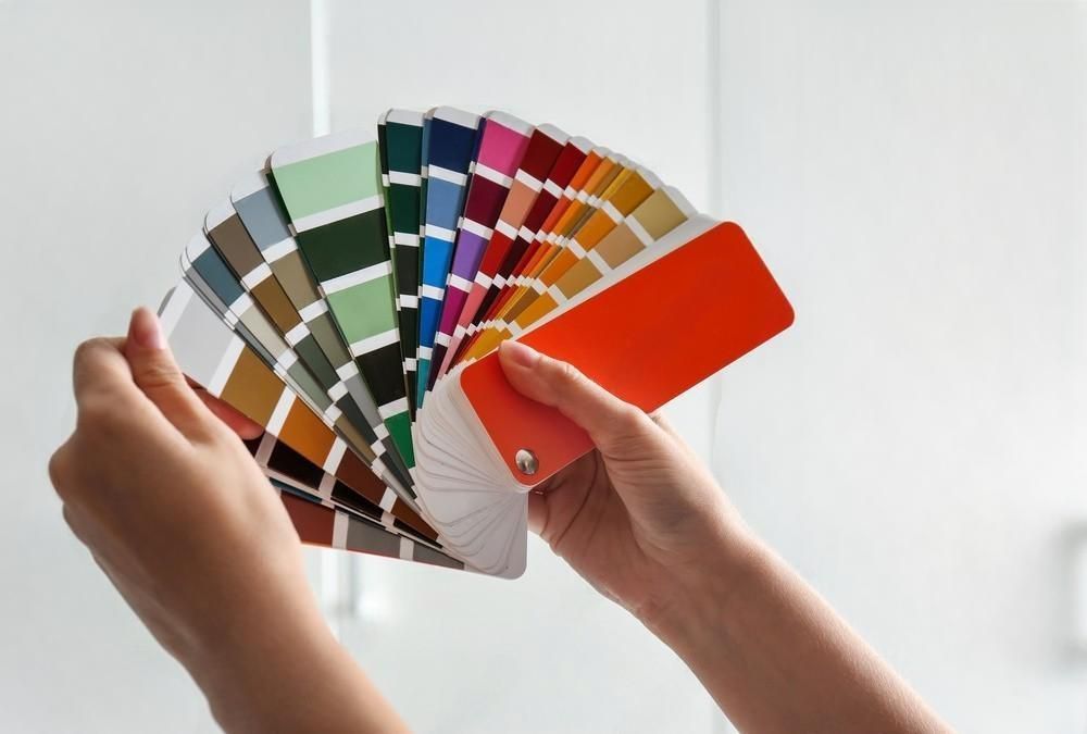 A person is holding a fan of color swatches in their hands.