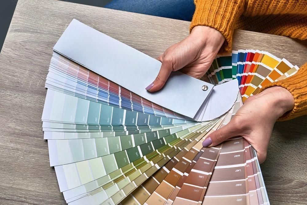 A person is holding a fan of paint samples in their hands.