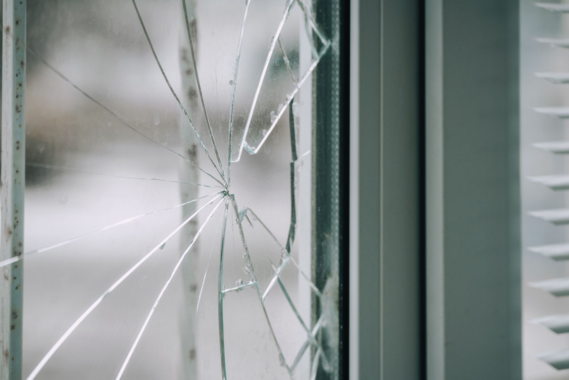 Glass broken by hooligans in a metal-plastic window, close-up.