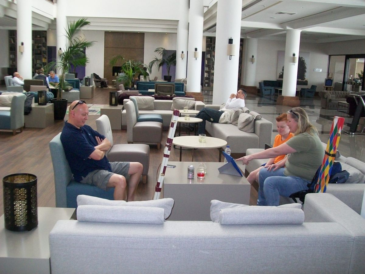 Mensen in de lobby van een hotel met witte pilaren, zachte zitplaatsen en natuurlijk licht.