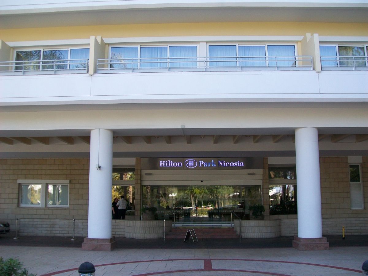 De ingang van het Hilton Hotel met witte zuilen, glazen deuren en het Hilton-logo.