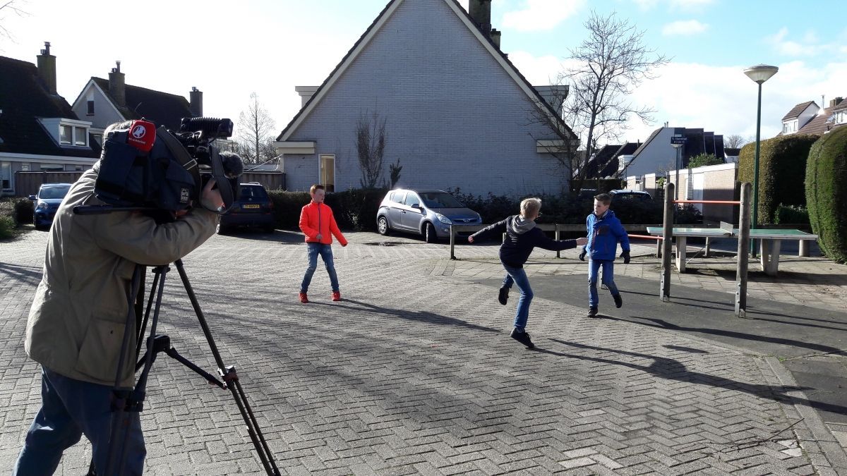 Cameraman filmt drie kinderen die op een zonnige dag buiten spelen.