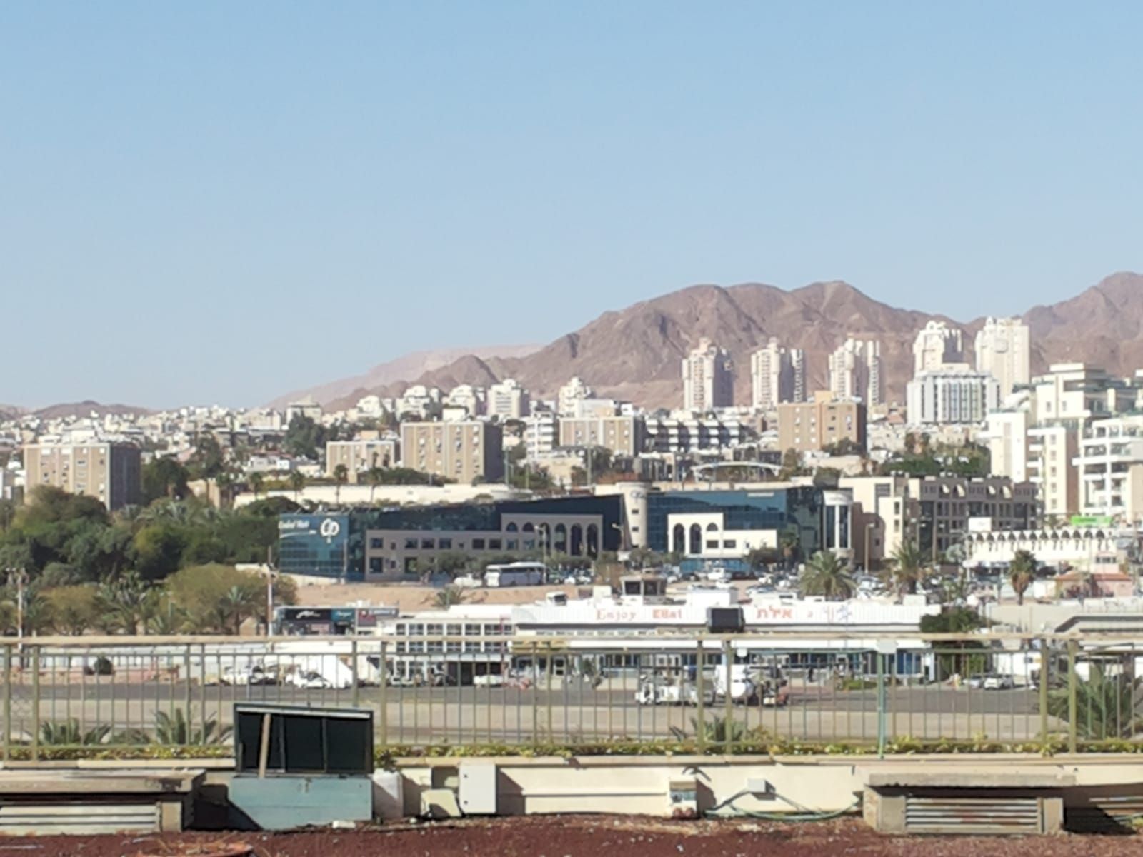 Stadsgezicht met gebouwen, bergen op de achtergrond onder een blauwe lucht.