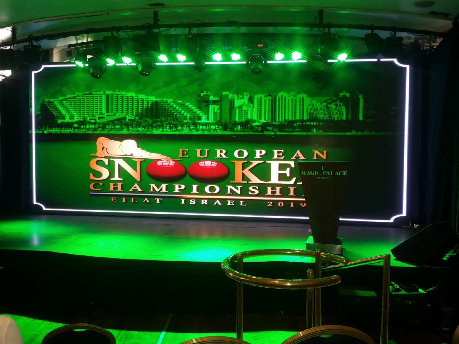 Podium voor het Europees Kampioenschap Snooker in Eilat, Israël, met groene verlichting en logo.