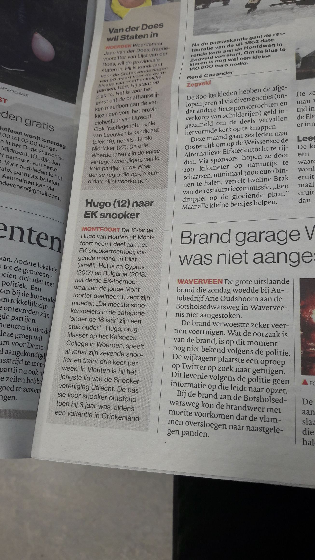 Krantenpagina's met tekstkolommen in zwart, tegen een wazige, lichte achtergrond.