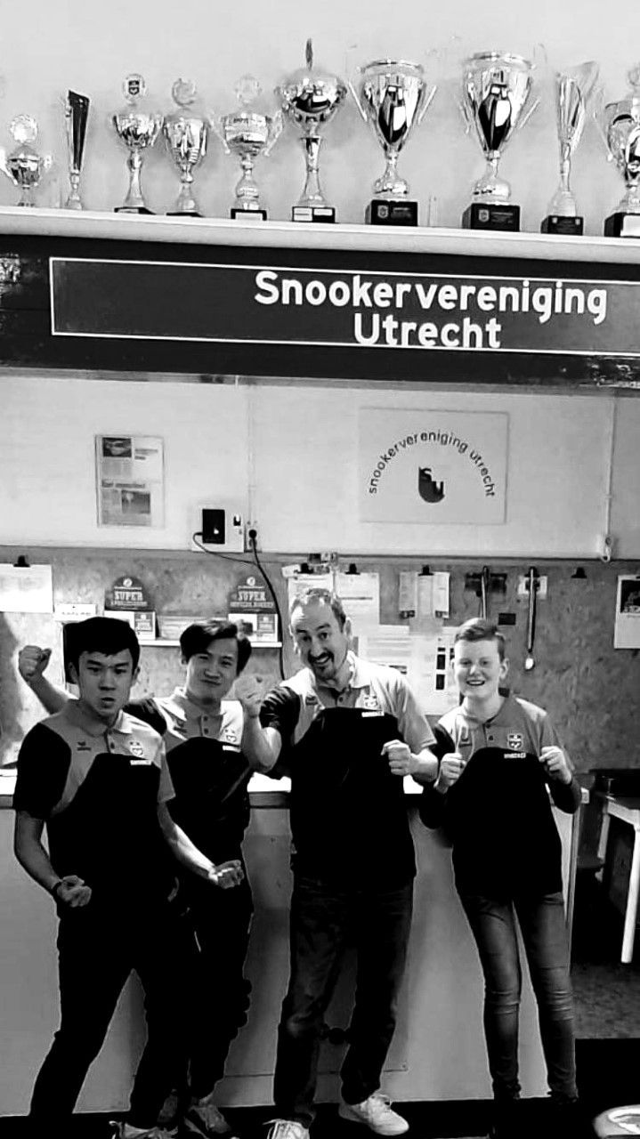 Vier feestvierende mensen, met gebalde vuisten, bij de club 