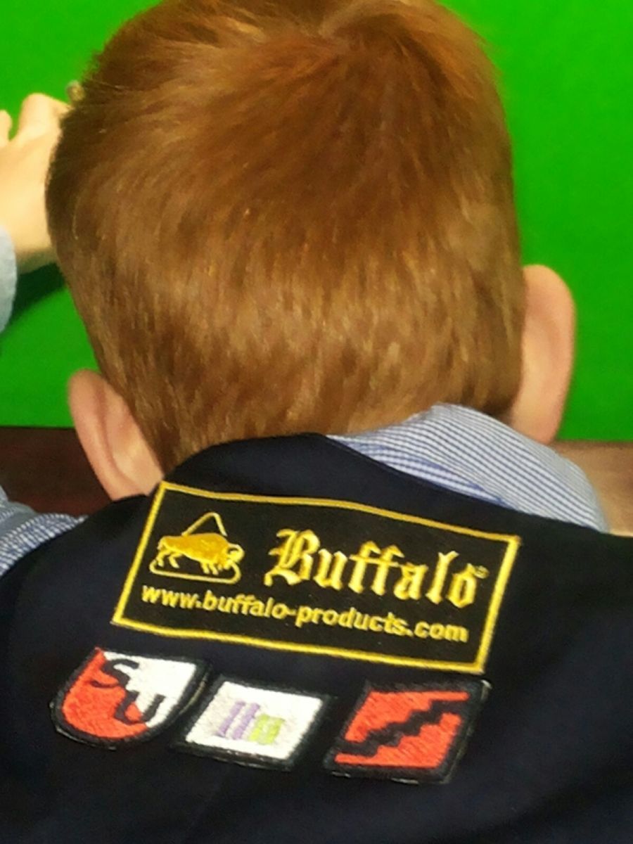 Achteraanzicht van een persoon met rood haar, die een jas draagt ​​met het 