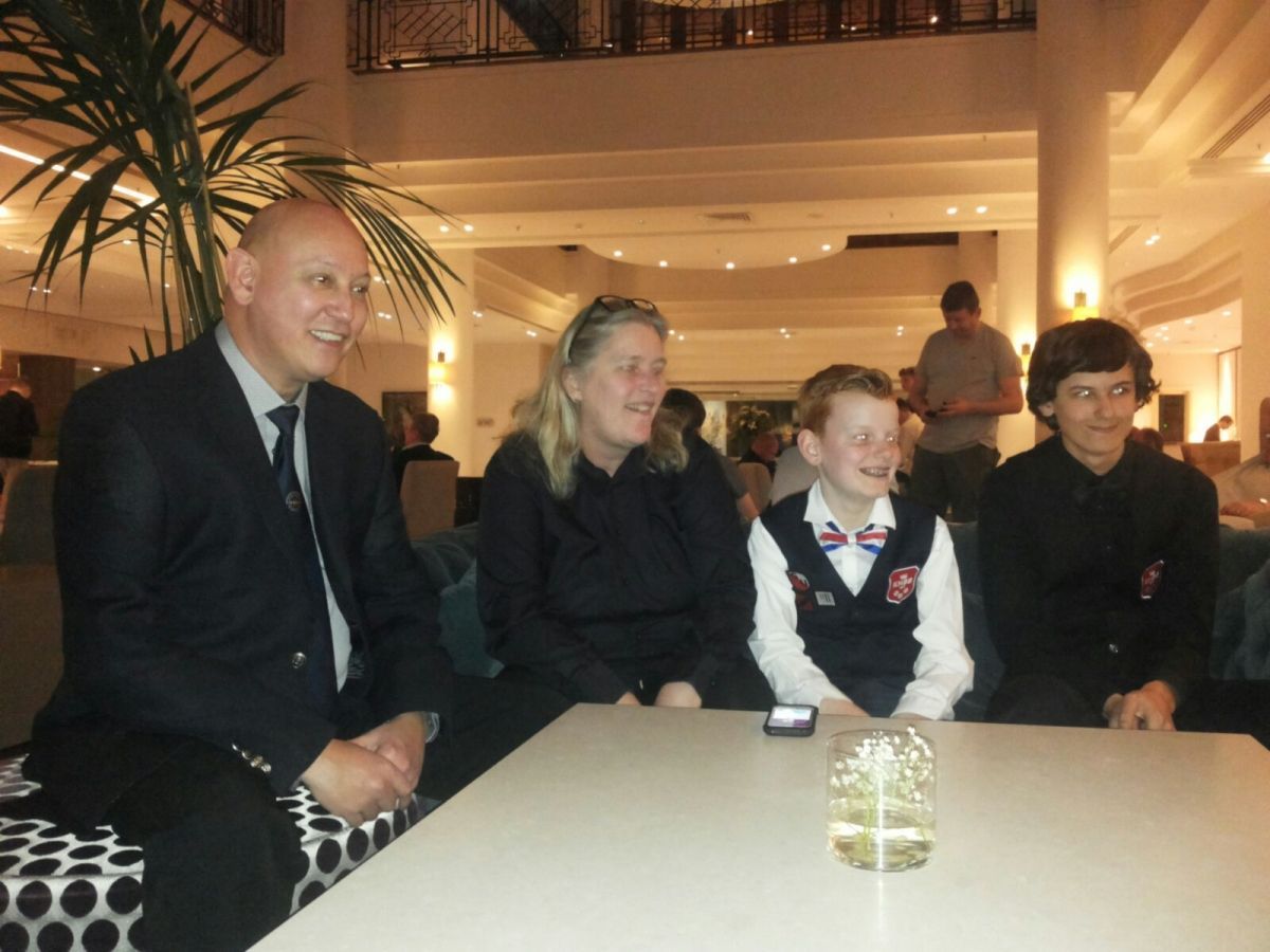 Een groep van vier mensen zit aan een tafel in een goed verlichte kamer. Ze lijken te glimlachen.