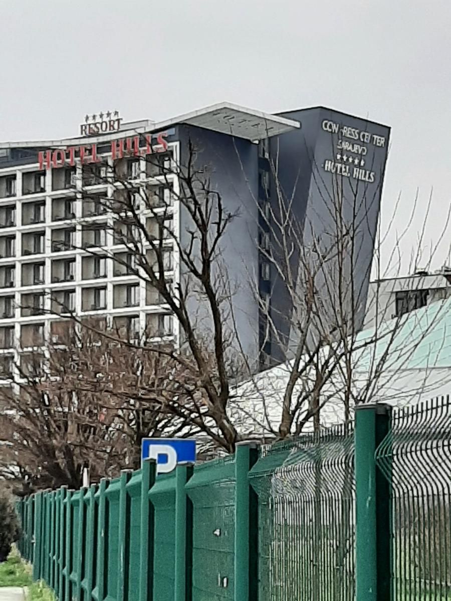 Hotelgebouw met hoge, moderne architectuur en een hek ervoor.