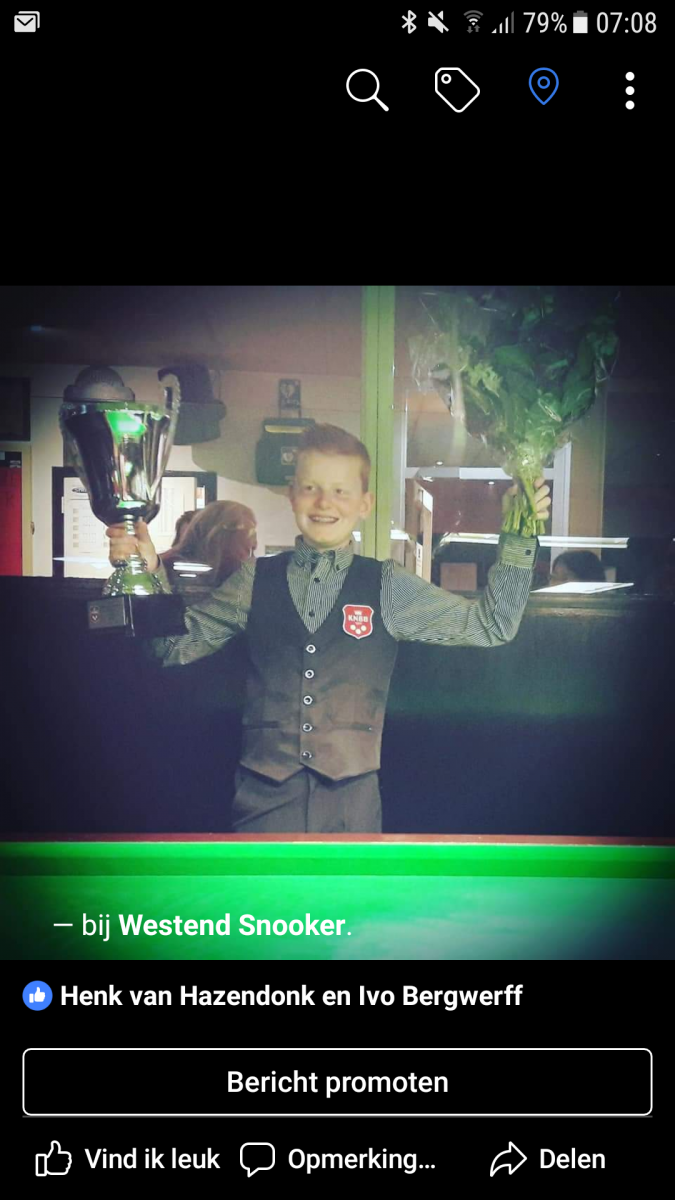 Een jonge jongen in een vest houdt een trofee en bloemen vast en viert feest in een snookerhal.