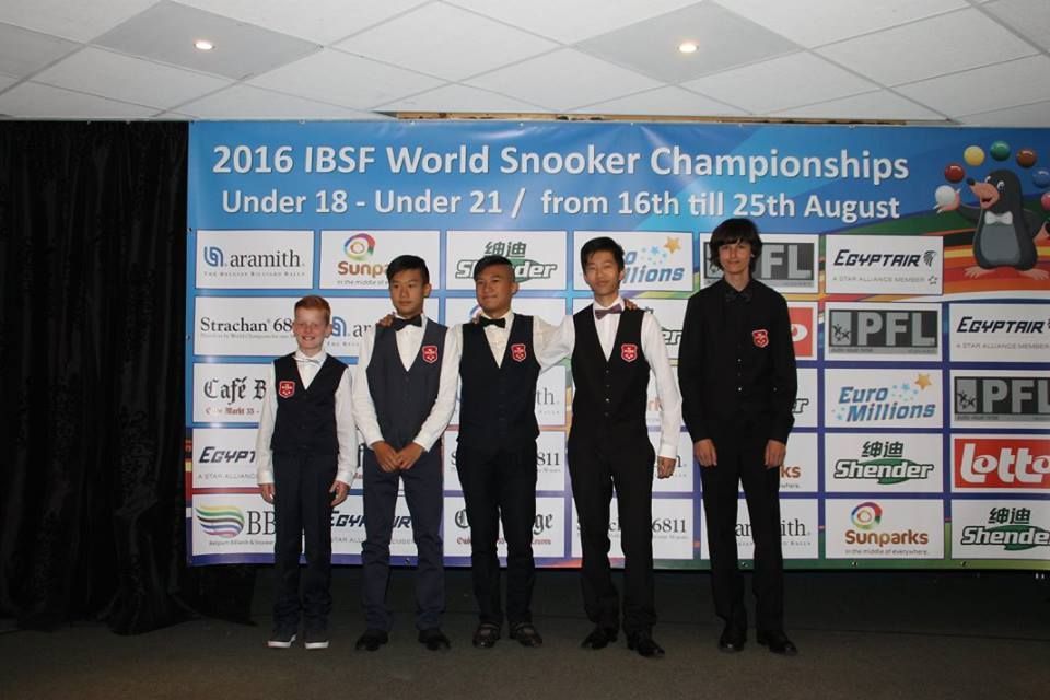 Vijf jongemannen in pakken poseren voor een spandoek voor de IBSF World Snooker Championships van 2016.