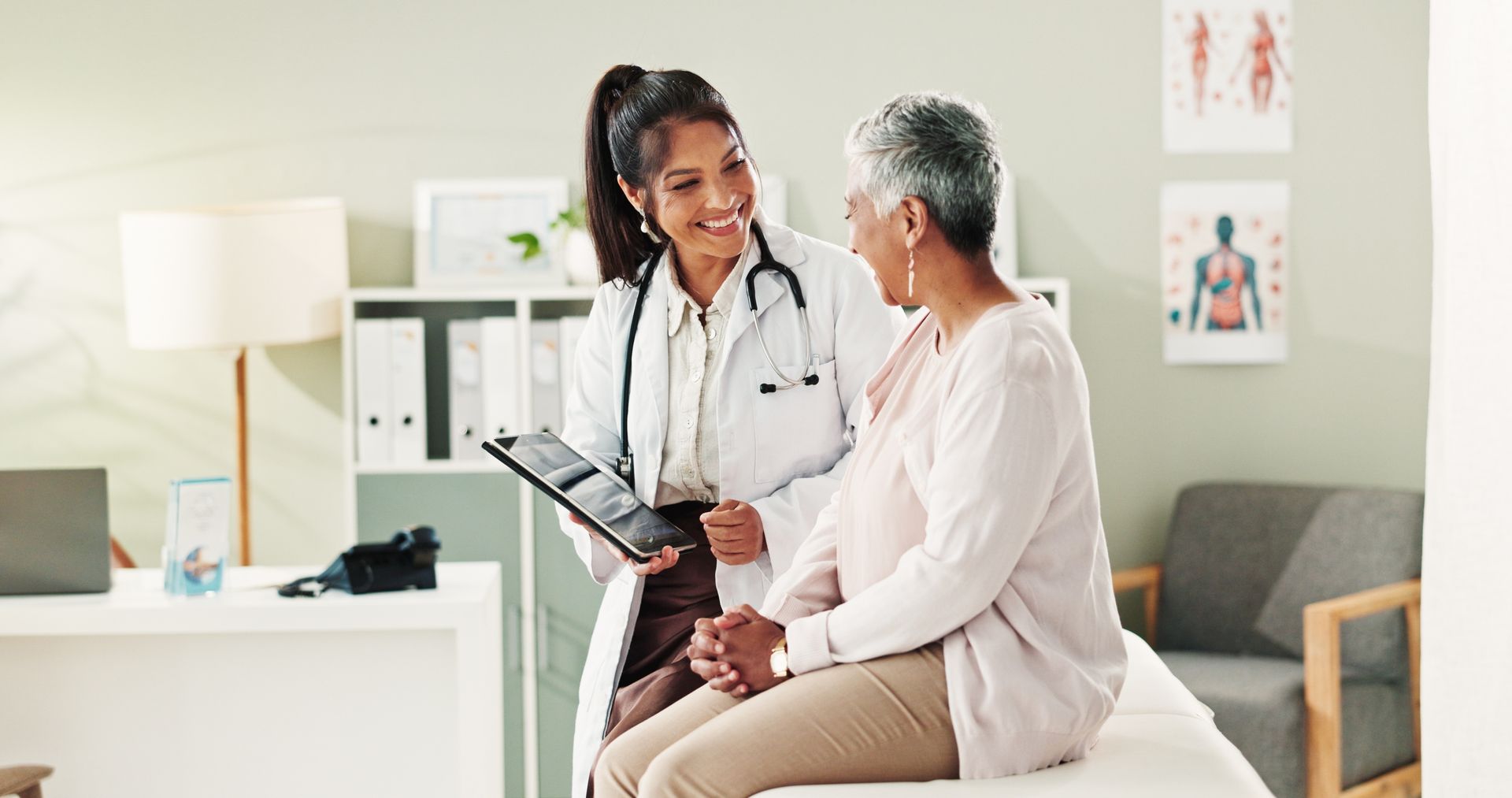 Doctor and patient smiling and reviewing documents in an exam room.
