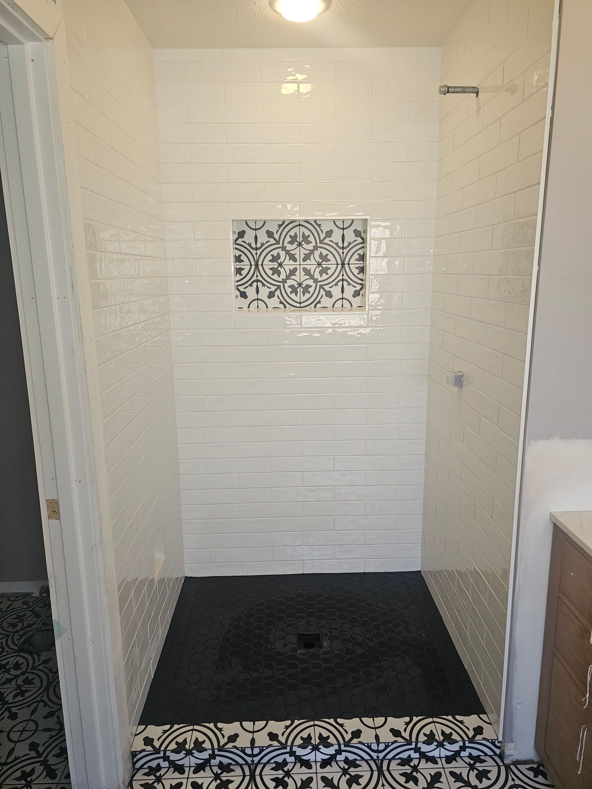 A bathroom with a walk in shower and a black tile floor.