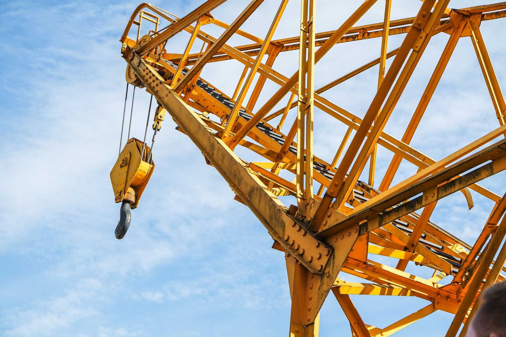 View from the bottom up to a yellow crane against the blue sky.