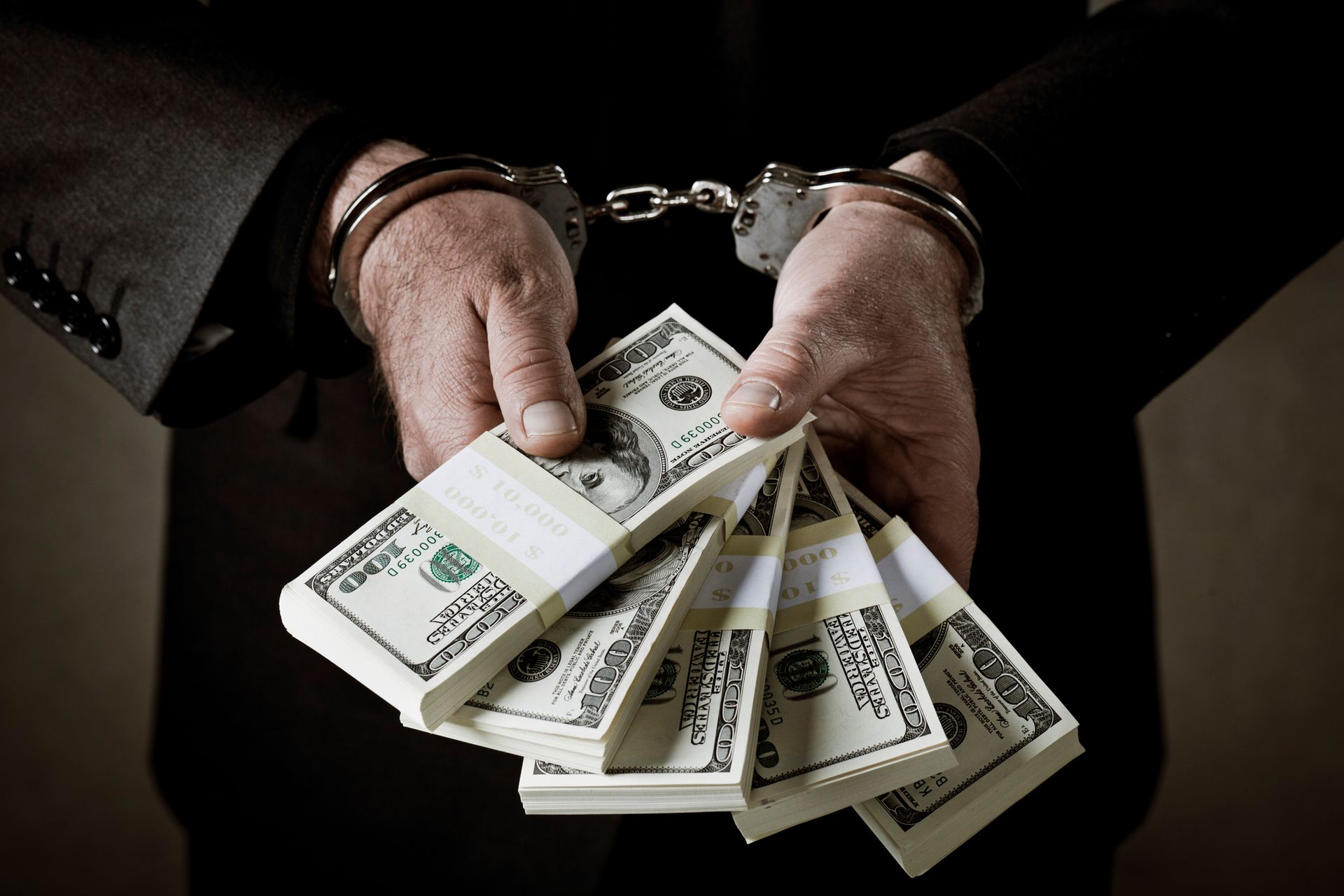 An arrested man in handcuffs is holding money. An arrested man in handcuffs is holding money.
