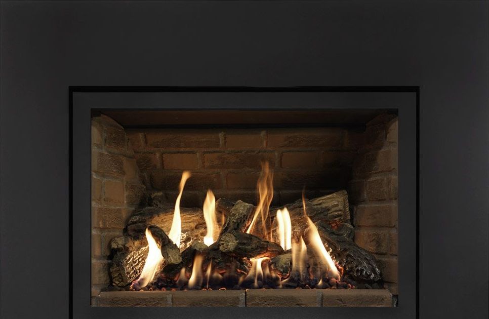 A fireplace with a lot of logs in it and flames coming out of it.