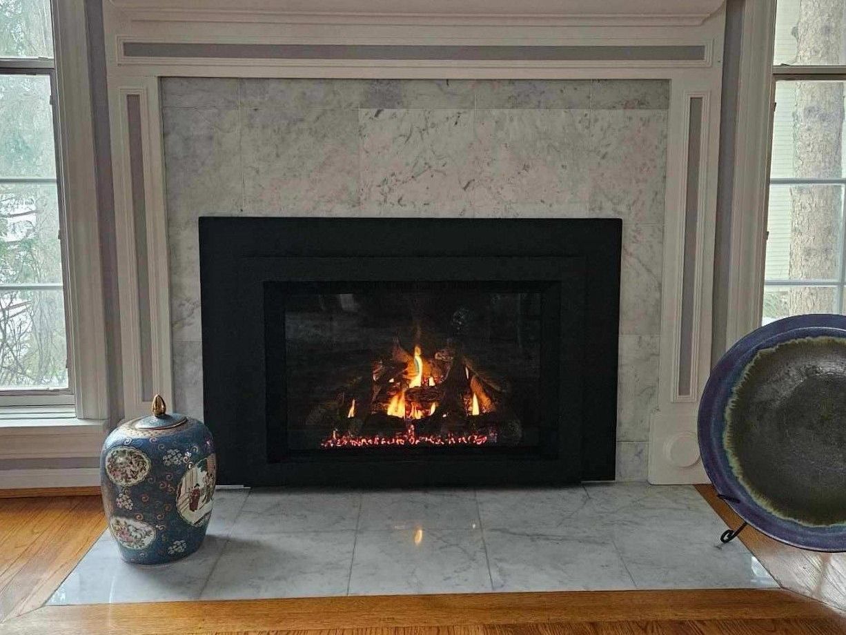 A living room with a fireplace and a vase on the floor.