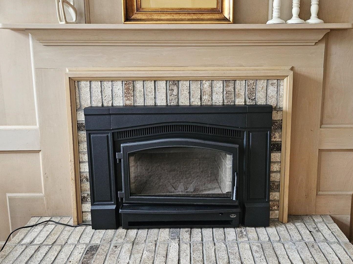 A fireplace with a wood stove in it and a brick mantle.
