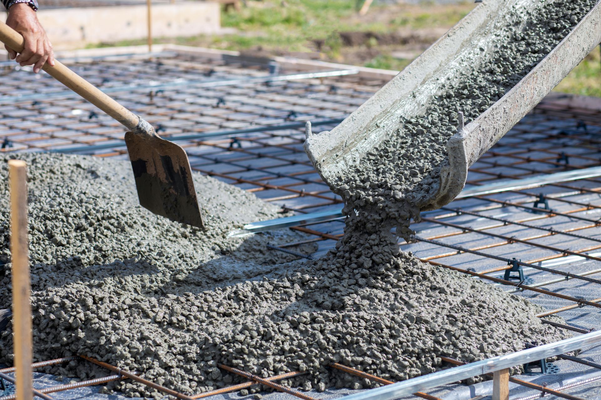 Worker takes concrete from a mixer tray with a shovel Worker takes concrete from a mixer tray with a shovel