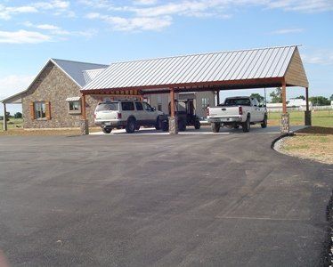 Two cars are parked under a carport in front of a house