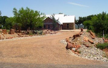 A house with a white roof is surrounded by rocks and trees