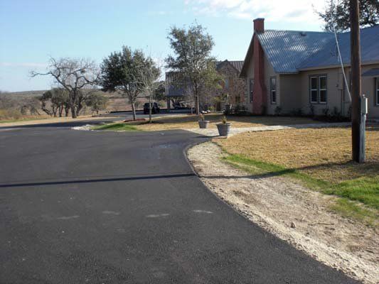 A house is sitting on the side of a road next to a dirt road.