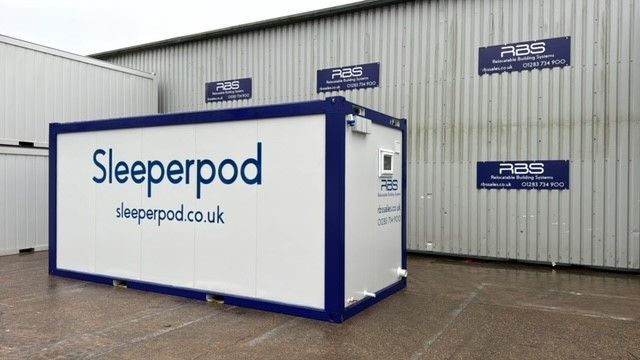 A sleeperpod is sitting in front of a building.