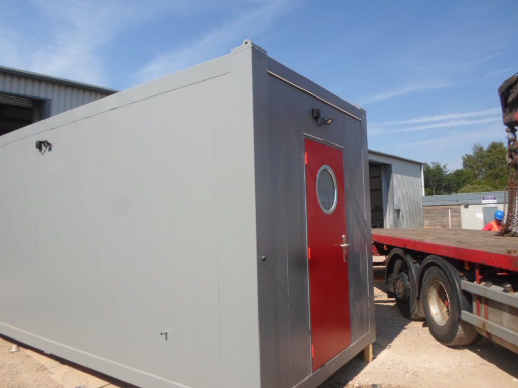 A large grey portable cabin featuring a red door