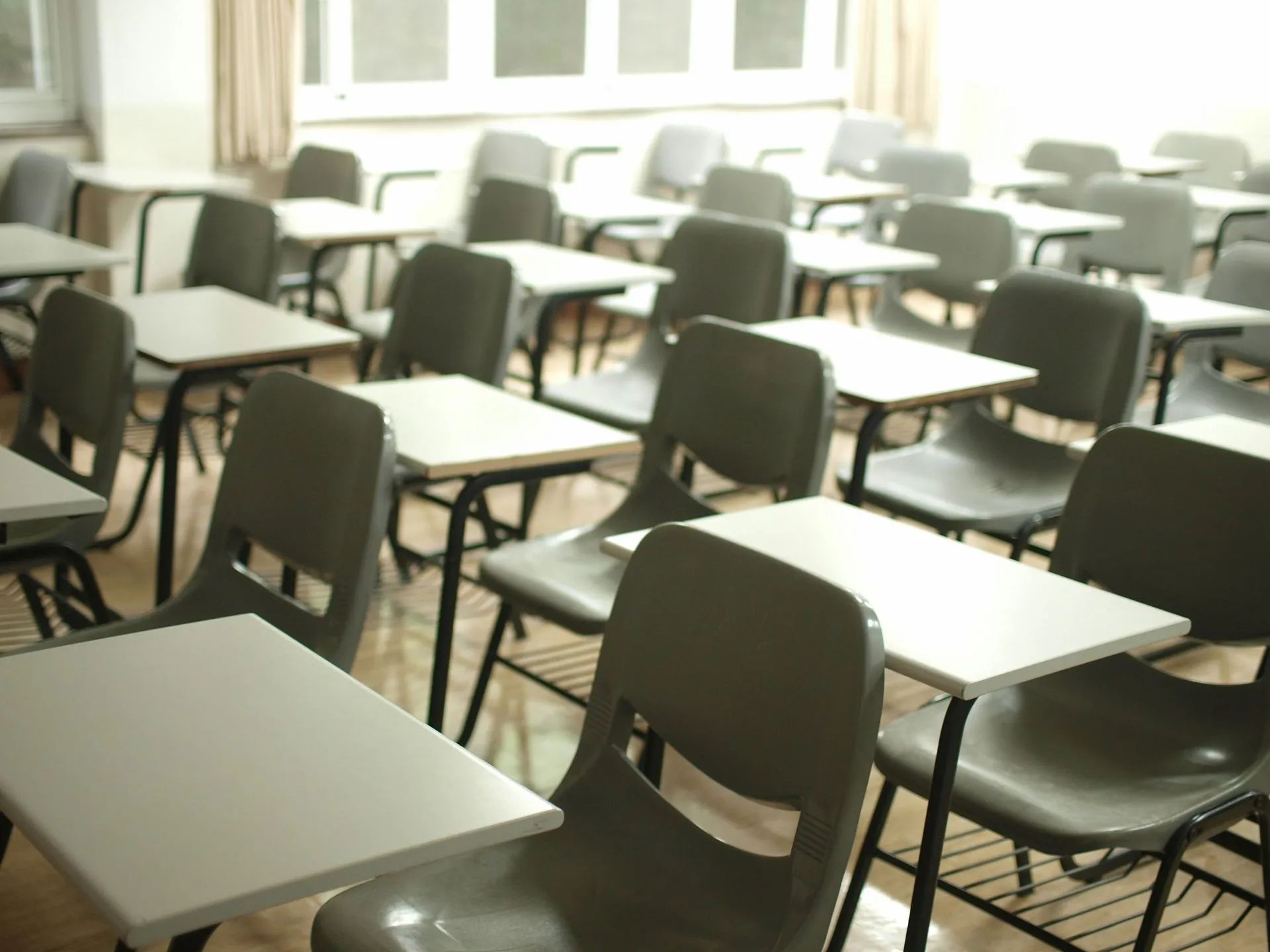 Classroom with rows of desks and chairs, window with curtains in the background
