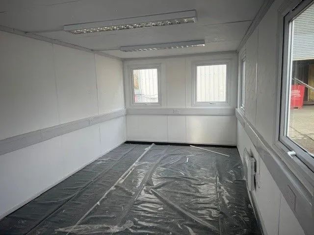 Empty room with windows and plastic sheets covering the floor