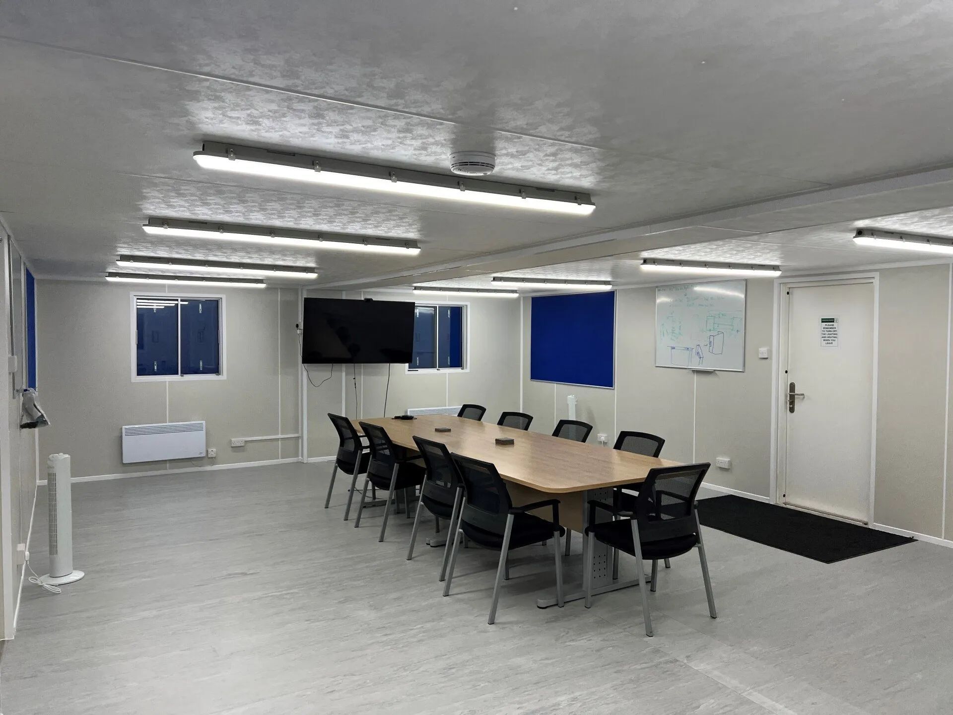 Office inside a portakabin with a wall-mounted TV and ceiling lights