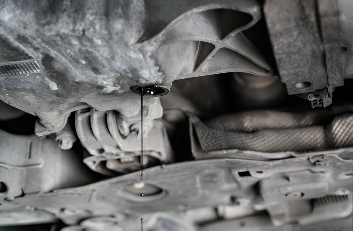 A close up of a person pouring oil into a car.