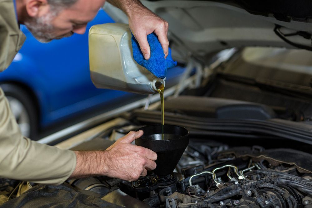 A man is pouring oil into a car engine.