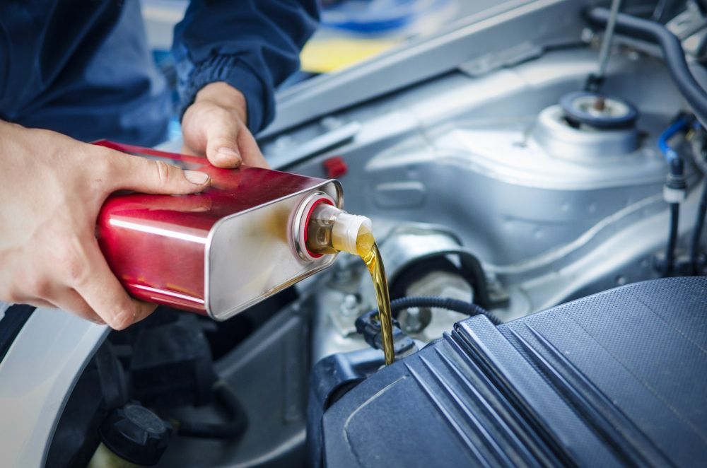 A person is pouring oil into a car engine.