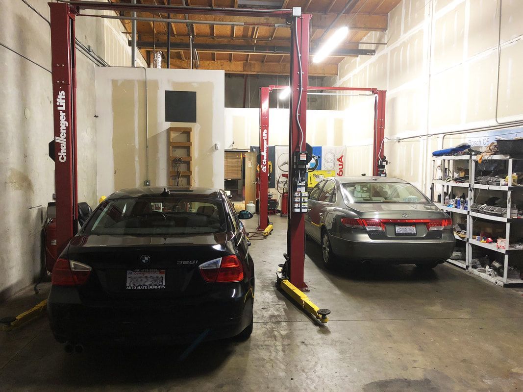 Two cars are sitting on a lift in a garage.