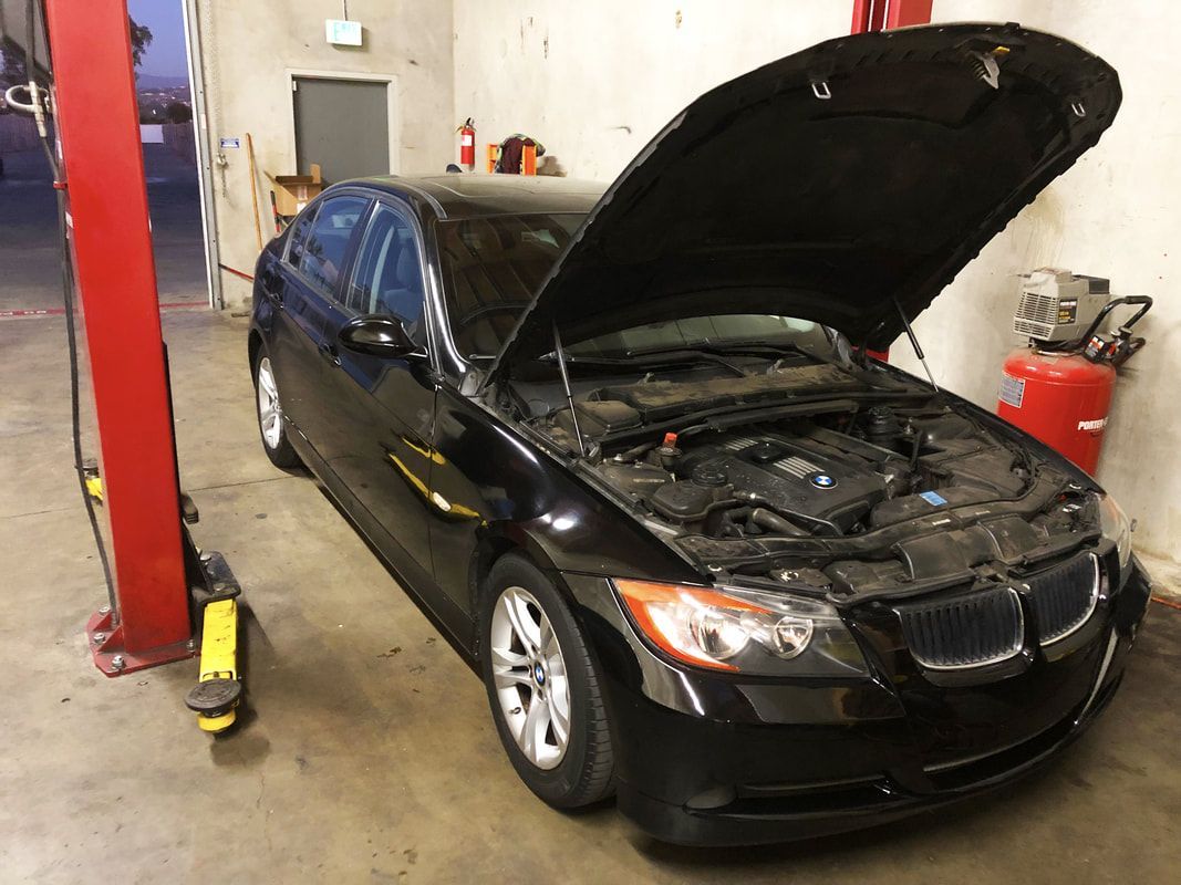 A black car with the hood up in a garage