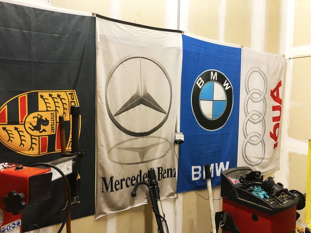 A row of mercedes benz bmw and audi flags hanging on a wall