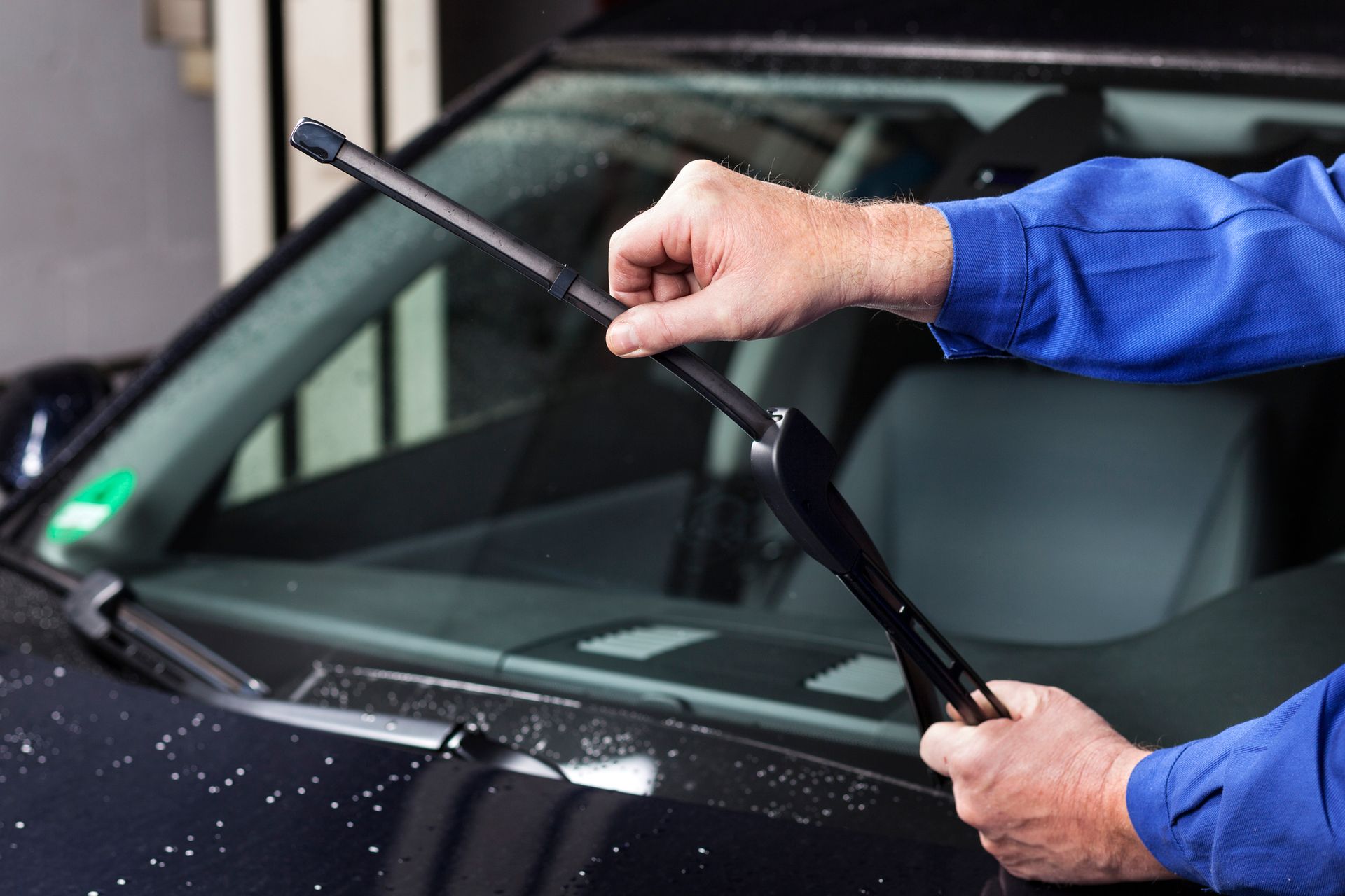 A man is holding a device in front of a car engine.