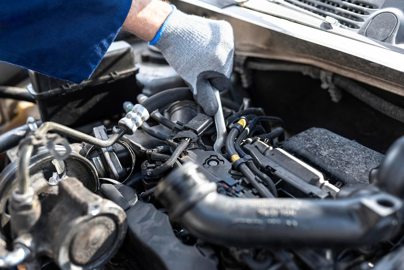 A man is working on the engine of a car with a wrench.