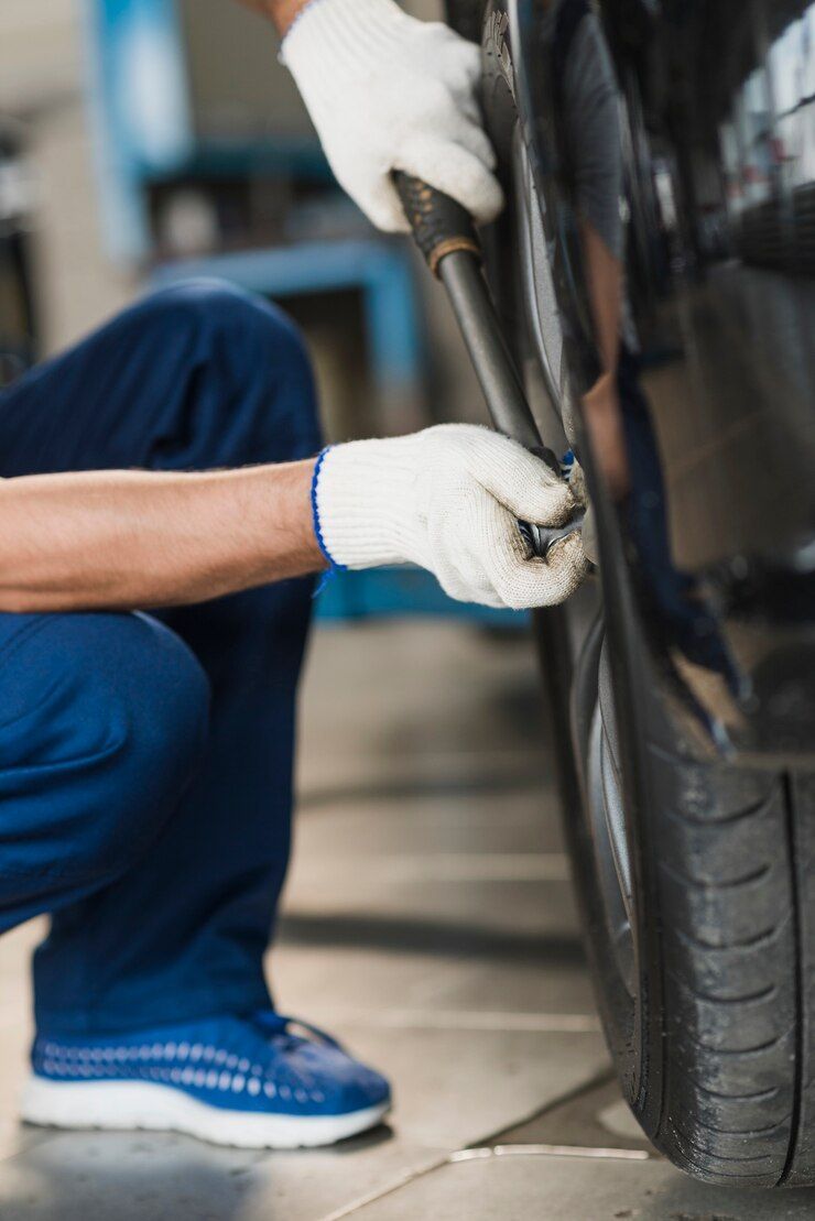 A man is holding a device in front of a car engine.