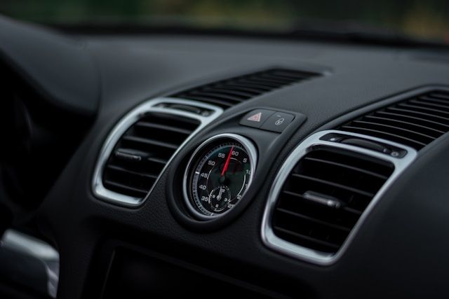A close up of a car dashboard with air vents and a clock.