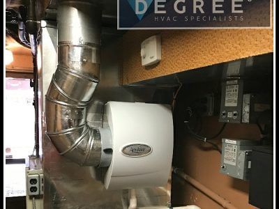 Humidifier installed with ductwork in a utility room.