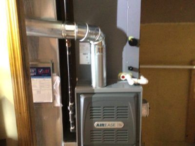 AirEase furnace with exhaust pipe in a utility room.